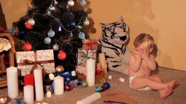 Un niño pequeño está jugando cerca de un árbol de Navidad — Vídeos de Stock
