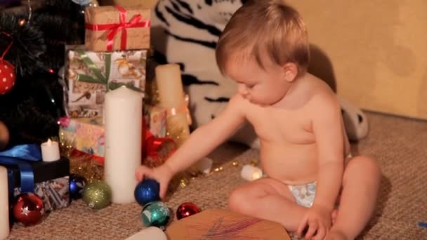 Ett litet barn spelar nära en julgran — Stockvideo