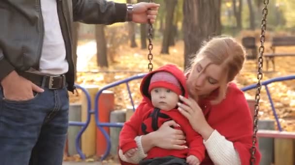 Family rides on a swing in a recreation park — Stock Video