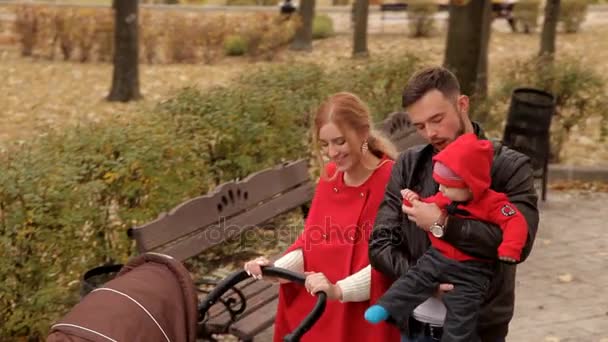 Familia joven con un niño pasea por el parque a principios de otoño — Vídeo de stock