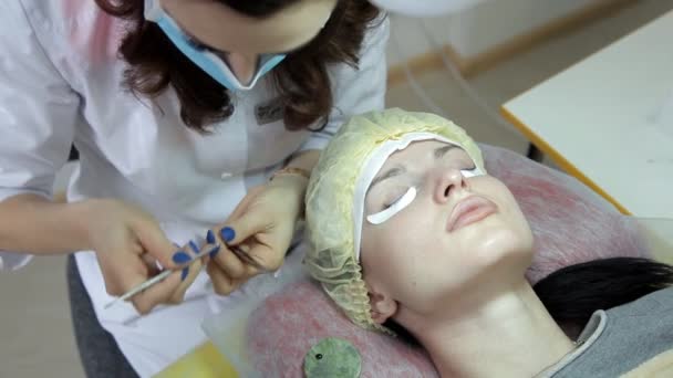 Kosmetolog utför ögonfransförlängning till klienten. Uppdatera ögonfransarna — Stockvideo