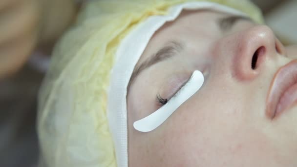 The cosmetologist performs eyelash extensions to the client. Update the eyelashes — Stock Video