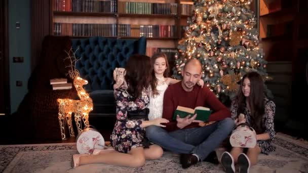 V novoroční atmosféře otec čte knihu k rodině — Stock video