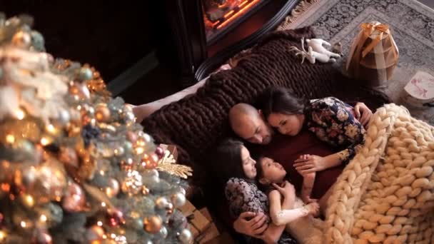 De vader met zijn vrouw en twee mensen is liggend op het bed in de sfeer van het nieuwe jaar. Op kerstavond en gelukkige familie — Stockvideo