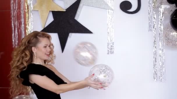 Chica carismática en un vestido negro arroja globos. Ambiente festivo — Vídeos de Stock