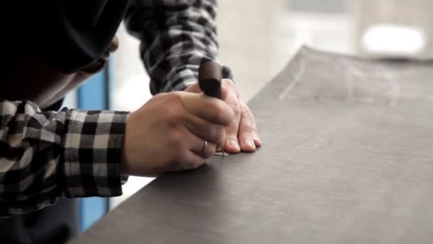 Un maître d'un gouvernail en cuir coupe des billettes pour fabriquer une ceinture. Procédure de fabrication des ceintures en cuir . — Video