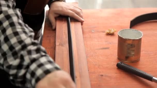 En el taller, un especialista agudiza un cinturón de cuero. Procedimiento para la fabricación de cinturones de cuero — Vídeo de stock