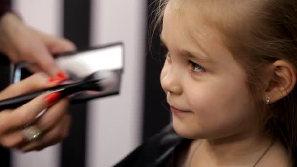 In the beauty studio of a little girl doing a haircut and applying makeup — Stock Video