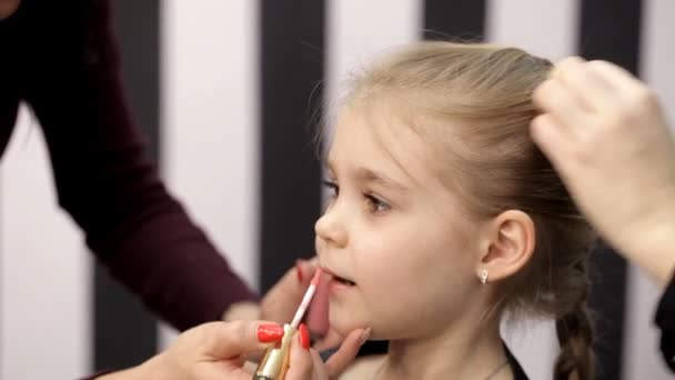 En el estudio de belleza de una niña haciendo un corte de pelo y aplicando maquillaje — Vídeos de Stock