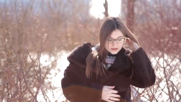 Menina bonito com óculos e casaco de pele de vison e alisamento do cabelo fora no inverno — Vídeo de Stock