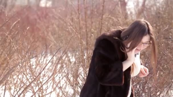 Vacker flicka är promenader runt snötäckta staden och talar på sin mobiltelefon — Stockvideo