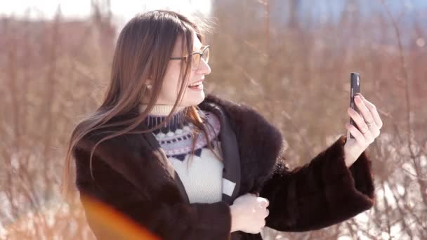 Beautiful girl in a snow-covered winter city using Skype on a smartphone communicates with his family — Stock Video