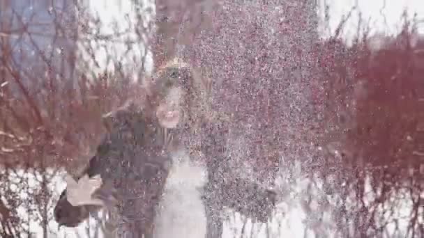 На заснеженном лугу зимой городская девушка бросает снег и радуется — стоковое видео