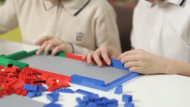 Двоє хлопчиків зводять будівлі від дизайнера дитячого пластику — стокове відео