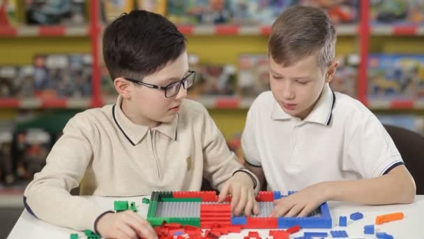 Dois meninos erguem edifícios de um designer de plástico infantil — Vídeo de Stock