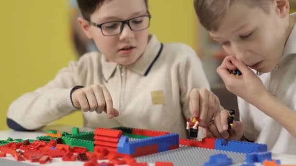 Bei der Ausstellung von Spielzeug spielen zwei Jungen mit Plastikbausteinen für Kinder — Stockvideo