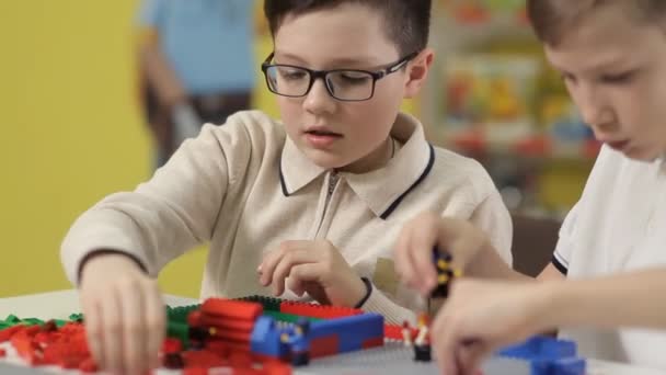 Bei der Ausstellung von Spielzeug spielen zwei Jungen mit Plastikbausteinen für Kinder — Stockvideo