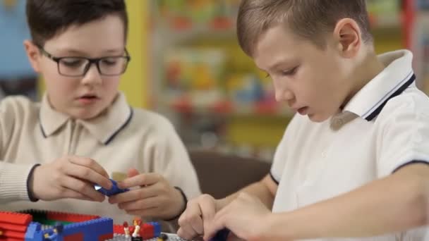 Na exposição de brinquedos, dois meninos brincam de blocos estruturais de plástico infantil — Vídeo de Stock