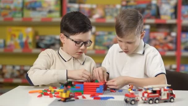 Nel centro di intrattenimento per bambini, due ragazzi raccolgono oggetti diversi da parti in plastica. — Video Stock
