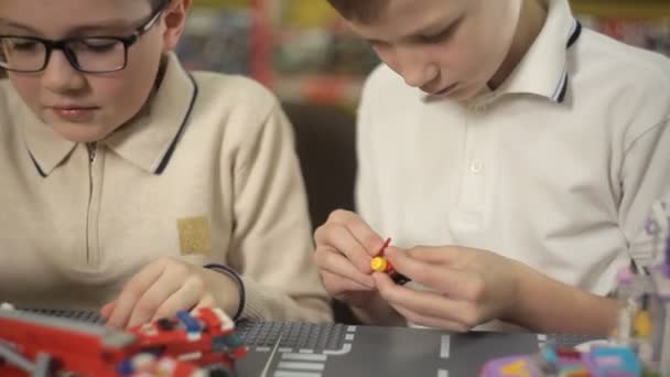 Два мальчика играют с композициями от пластикового дизайнера — стоковое видео