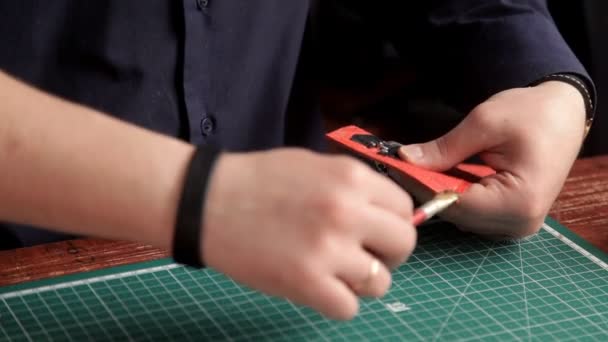 En el taller, un hombre pega las piezas de la piel, haciendo una billetera — Vídeo de stock