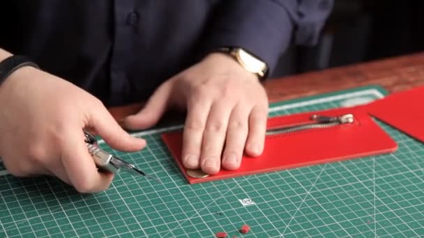 Чоловік вирізає зайву шкіру з заготовки під гаманець — стокове відео