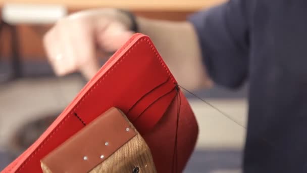 Man with his hands makes a leather wallet. A man of leather stitching wallet-leather product — Stock Video