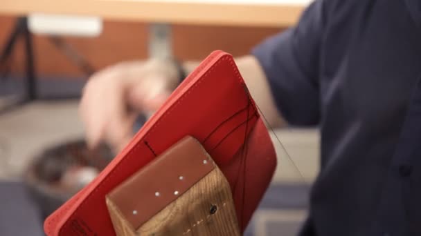Man med händerna gör en läder plånbok. En man av läder häftning plånbok läder produkt — Stockvideo