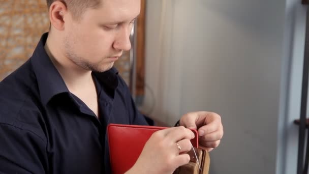 Στο εργαστήριο, ένας άνθρωπος ράψιμο δερμάτινα κομμάτια προς κατεργασία, κάνοντας ένα πορτοφόλι — Αρχείο Βίντεο