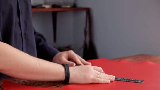 Handwerker zeichnet eine Markierungslinie auf das rote Ledertuch — Stockvideo