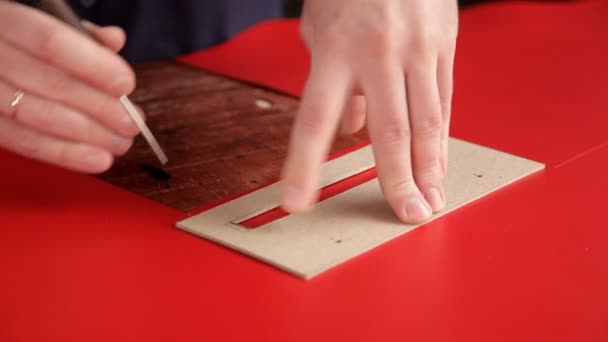 Řemeslník dělá řadu značení na červené kožené tkaniny — Stock video