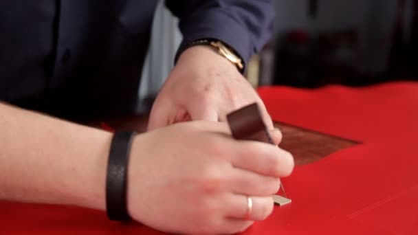 Řemeslník dělá řadu značení na červené kožené tkaniny — Stock video