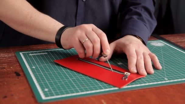Der Handwerker in der Werkstatt klebt die Lederrohlinge und macht das Lederprodukt — Stockvideo