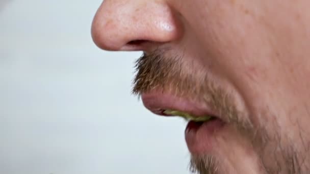 Gros plan homme avec une tranche de légumes dans la bouche, concept de mode de vie végétalien, vue de côté — Video