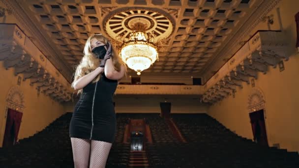 Маскована молода блондинка позує сексуально на сцені в концертному залі — стокове відео