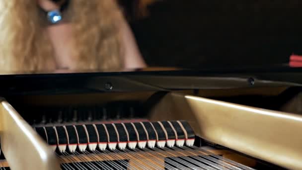 En tjej i svart klänning och med mask i ansiktet spelar piano. Ovanlig musikalisk föreställning. Pianosträngar — Stockvideo