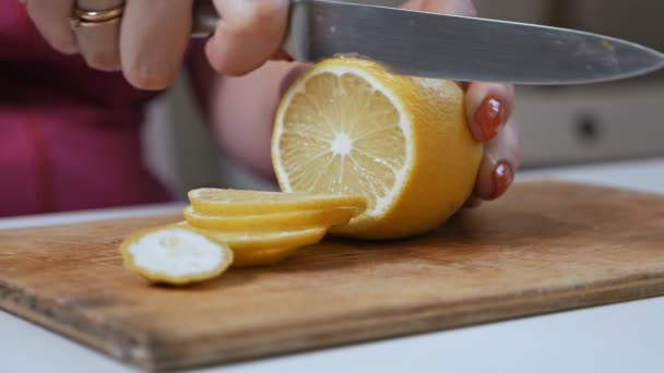 Gesneden citroen op houten snijplank.Vrouw die een citroen snijdt — Stockvideo