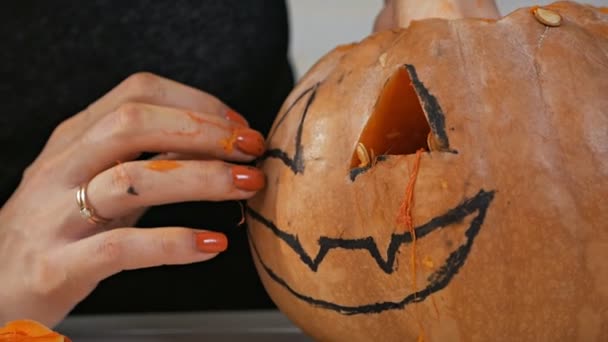 Orange pumpkin carved for the celebration of Halloween. A woman takes out the seeds and pulp of a pumpkin. Preparing the scenery for a traditional fall party. Crazy halloween — ストック動画