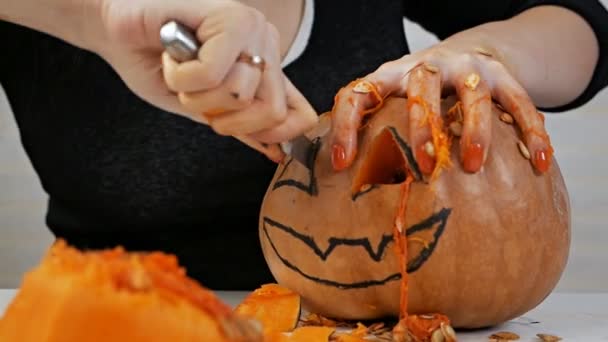 Женщина вырезает из тыквенного фонаря для празднования Хэллоуина — стоковое видео