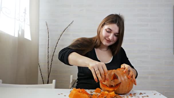 Eine Frau bereitet einen Kürbis für das Lenden zu, holt Kerne und Fruchtfleisch heraus — Stockvideo