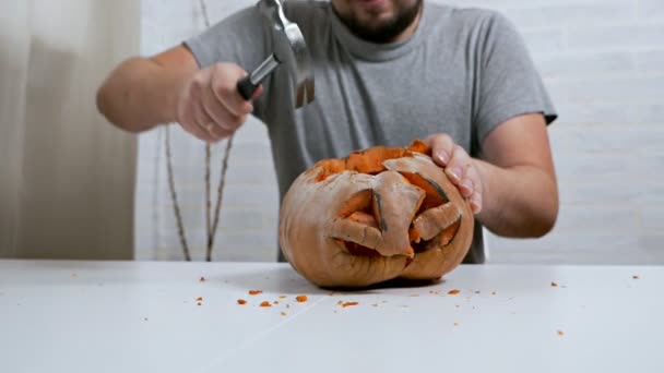 Een man met woede en agressie hamert een pompoen na Halloween — Stockvideo