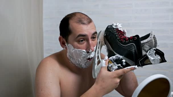 奇妙なことに、男はスケートからひげを剃る通常ではありません。髭を剃るときはスケートを使う。異常な顔の毛の除去、顔のスキンケア — ストック動画