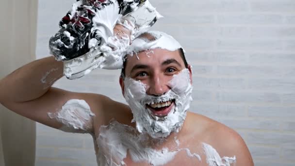 Um homem estranho rapa o cabelo na cabeça usando espuma de barbear e patins de hóquei, removendo o cabelo com uma lâmina de seus patins. Remoção de cabelo incomum de um homem real — Vídeo de Stock