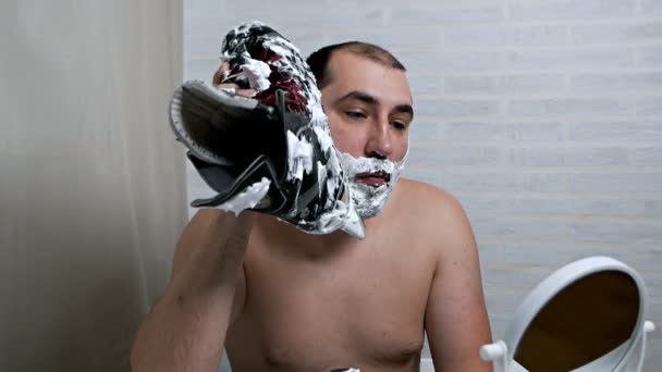 Extraño, no es lo habitual un hombre afeita la hoja de la barba de los patines. Un hombre usa patines al afeitarse la barba. Extracción de vello facial inusual, cuidado facial de la piel — Vídeos de Stock