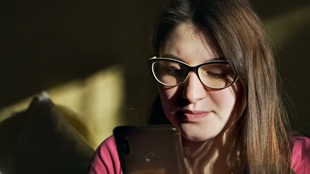 Νεαρή γυναίκα στέλνει μηνύματα στο smartphone στο σπίτι, διαβάζει ένα μήνυμα, περιηγείται στο Διαδίκτυο και χρησιμοποιεί την εφαρμογή — Αρχείο Βίντεο
