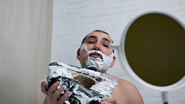 Barba pesada para hombre para afeitarse en casa. Un hombre se afeita la barba con un patín de hockey. — Vídeo de stock