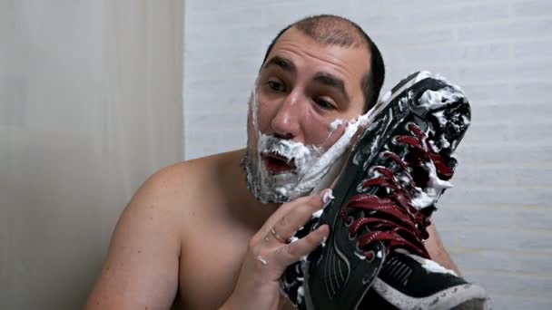 Barba pesada para hombre para afeitarse en casa. Un hombre se afeita la barba con un patín de hockey. — Vídeos de Stock
