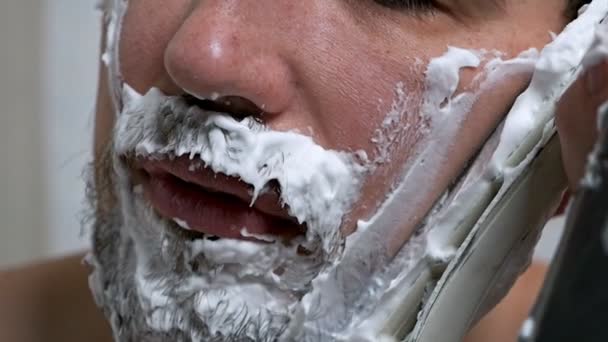 Barbe homme lourde pour le rasage à la maison. Un homme se rase la barbe avec un patin de hockey. — Video