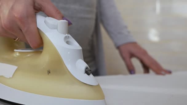 Wäsche bügeln zu Hause. Nahaufnahme der Hände einer jungen Frau, die Dinge glättet und Wasser mit einem Bügeleisen versprüht — Stockvideo