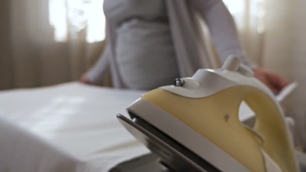 Schwangere Hausfrau streichelt. Eine junge schwangere Frau bügelt zu Hause. Wohnkomfort — Stockvideo